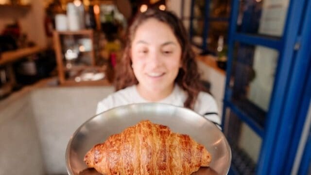 Croissant recién horneado en plato, servido en cafetería acogedora.