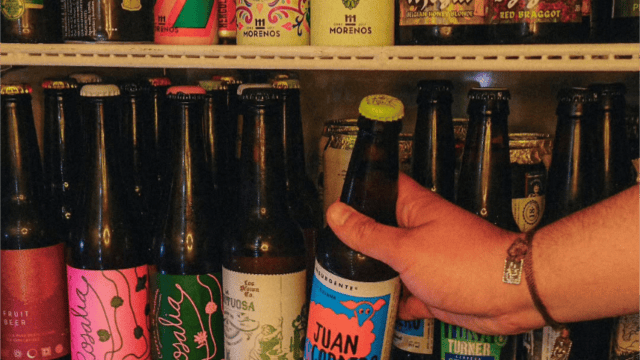 Cerveza artesanal en botella, exhibida en estantería con otras bebidas en tienda especializada.